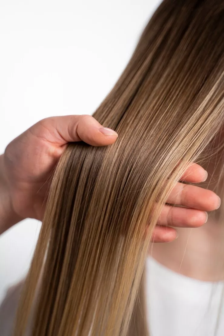 Mano sujetando un mechón de pelo de una mujer